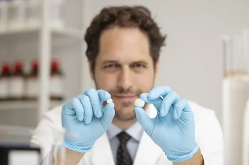 Aron Blaesi PhD ’14 holds two gastroretentive fibrous dosage forms, both before and after expansion due to water absorption.
