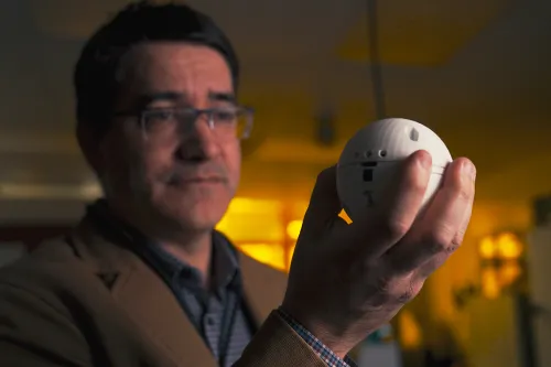 Researcher Jude Kelley holds up TOSSIT, an alerting sensor with a removable dye card that changes color in response to chemicals in the air.